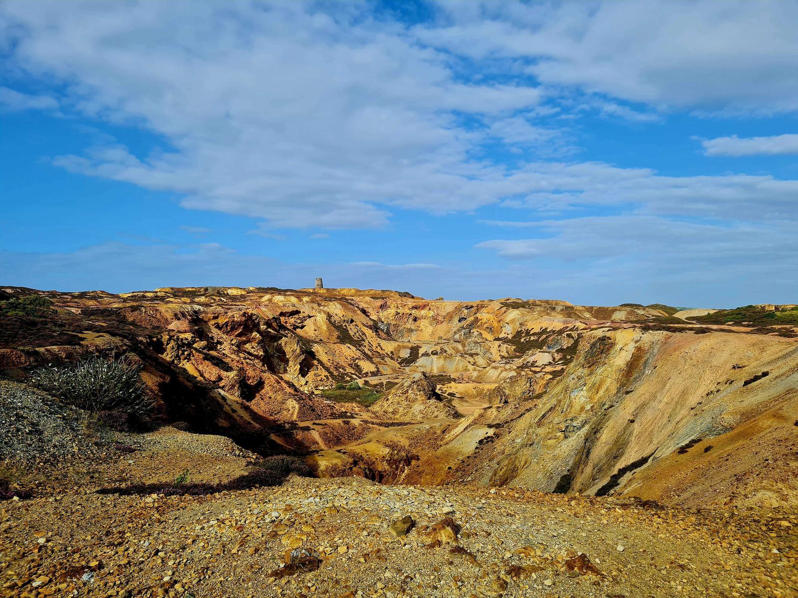 A photo of a landscape with golden shale slopes formed as a result of quarrying.
